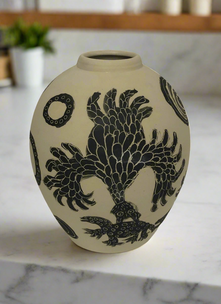 Painted vase by Mary Katatjuku Pan sitting on a marble surface.