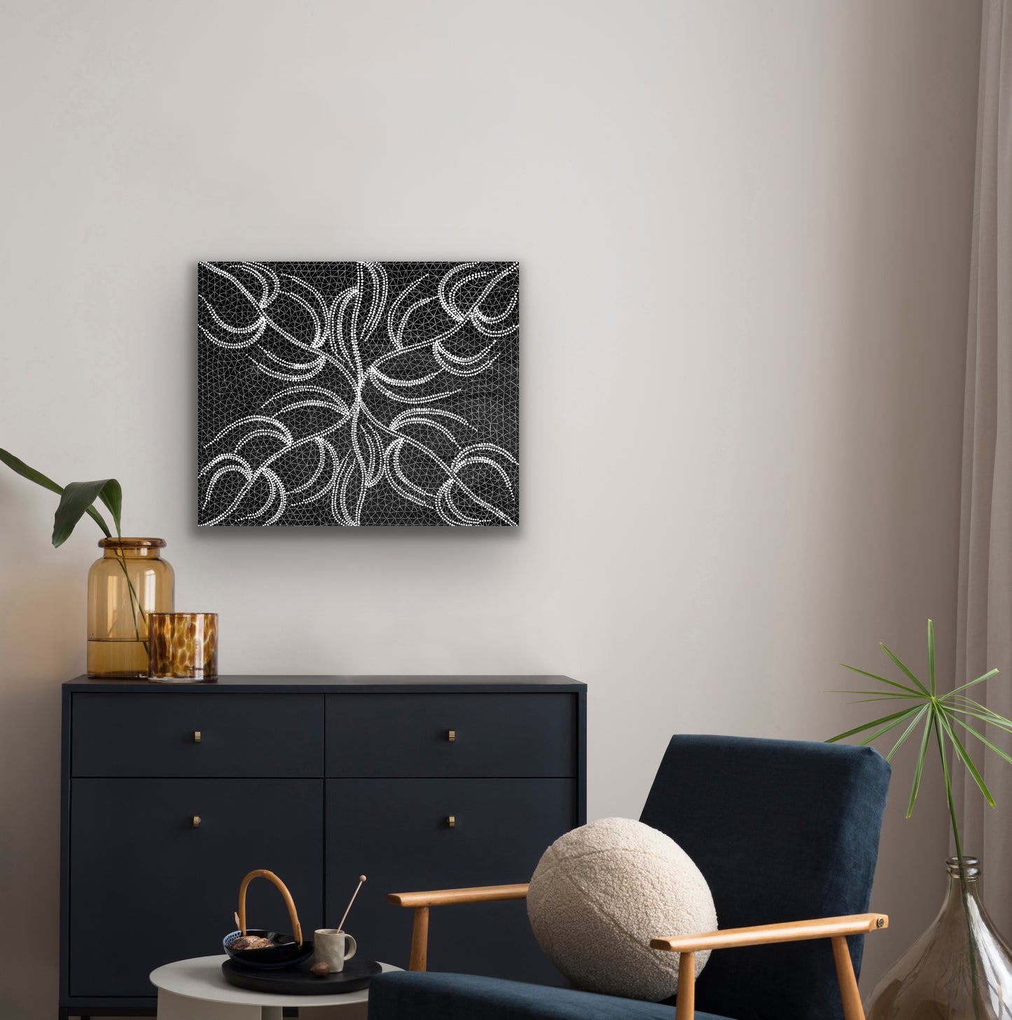 A black and white acrylic painting on canvas by Doreen Dickson Nakamarra depicting her damper seed dreaming, hanging on the wall above a black set of draws and a coffee table and armchair.