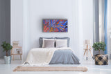 A 120x60cm painting by Gloria Petyarre hanging above a bed in a modern bedroom suite with a bed, abstract plants, side tables and a lamp.