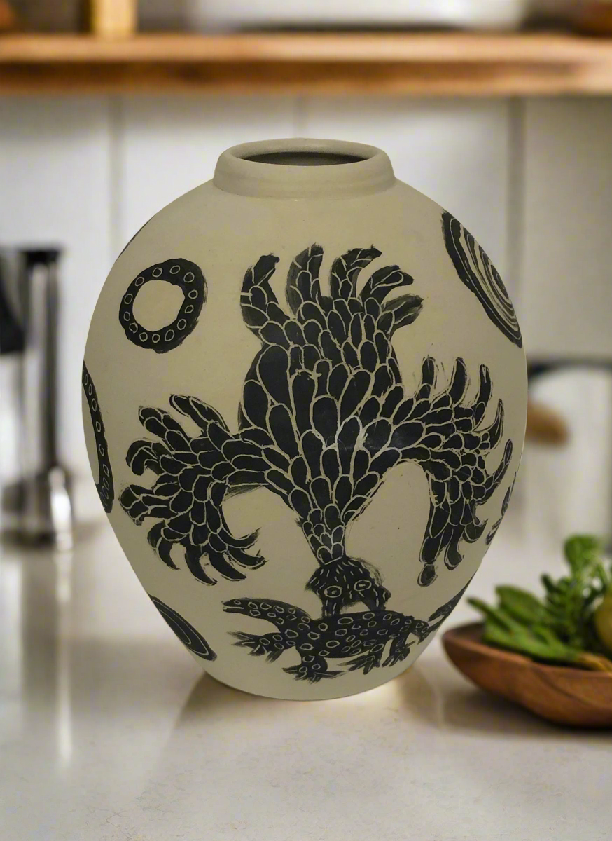 Painted vase by Mary Katatjuku Pan sitting on a kitchen counter.