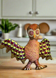 Decorative owl soft sculpture by Rhonda Sharpe with patterned, stitched feathers on a kitchen counter with cabinets and plants in the background