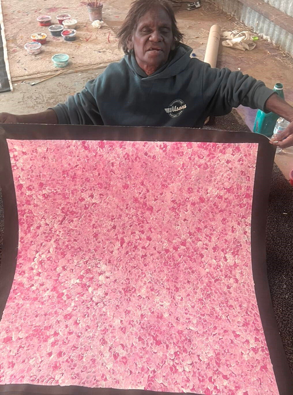 Bessie Pitjara holding her 'Anwekety (Bush Plum) dreaming' painting, 89x85cm