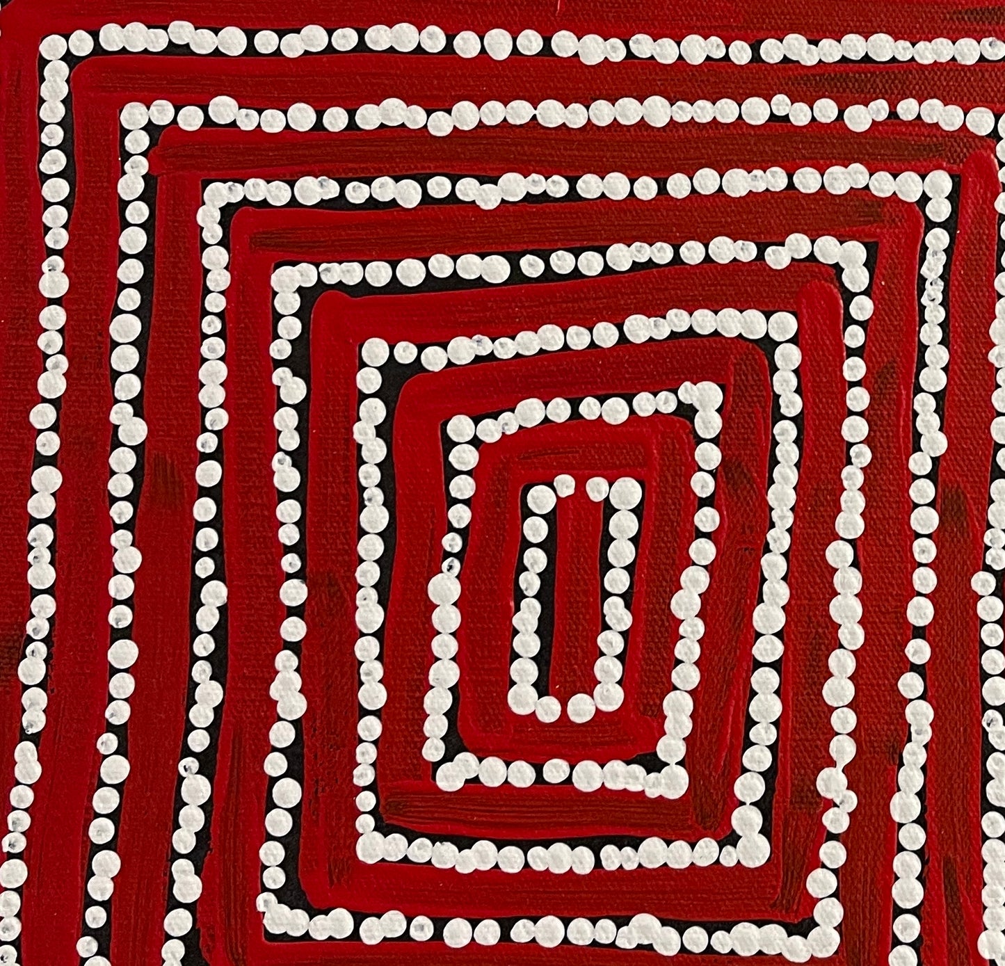 Close-up of a painting by Thomas Tjapaltjarri showing concentric lines with white dots on a red and black background