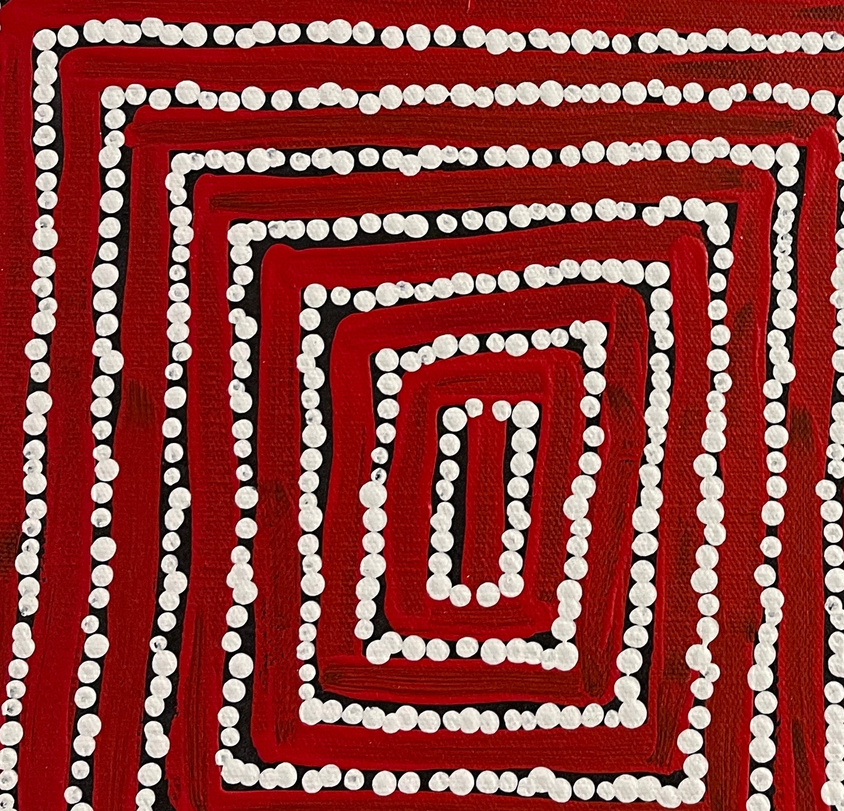Close-up of a painting by Thomas Tjapaltjarri showing concentric lines with white dots on a red and black background