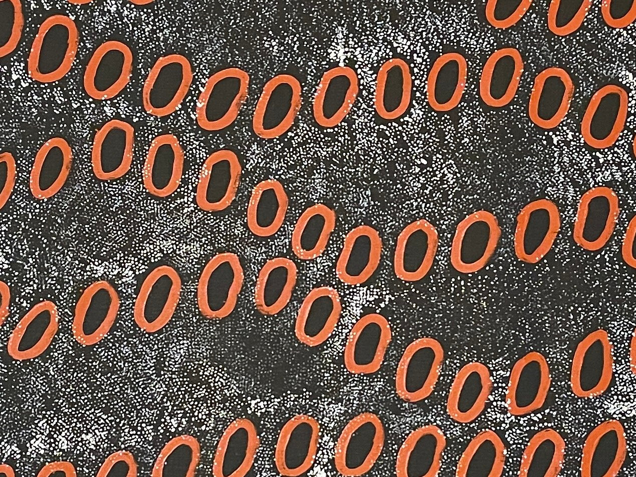 Close-up of a painting by Ngoia Pollard Napalptjarri. Red circles on a white dotted black background.