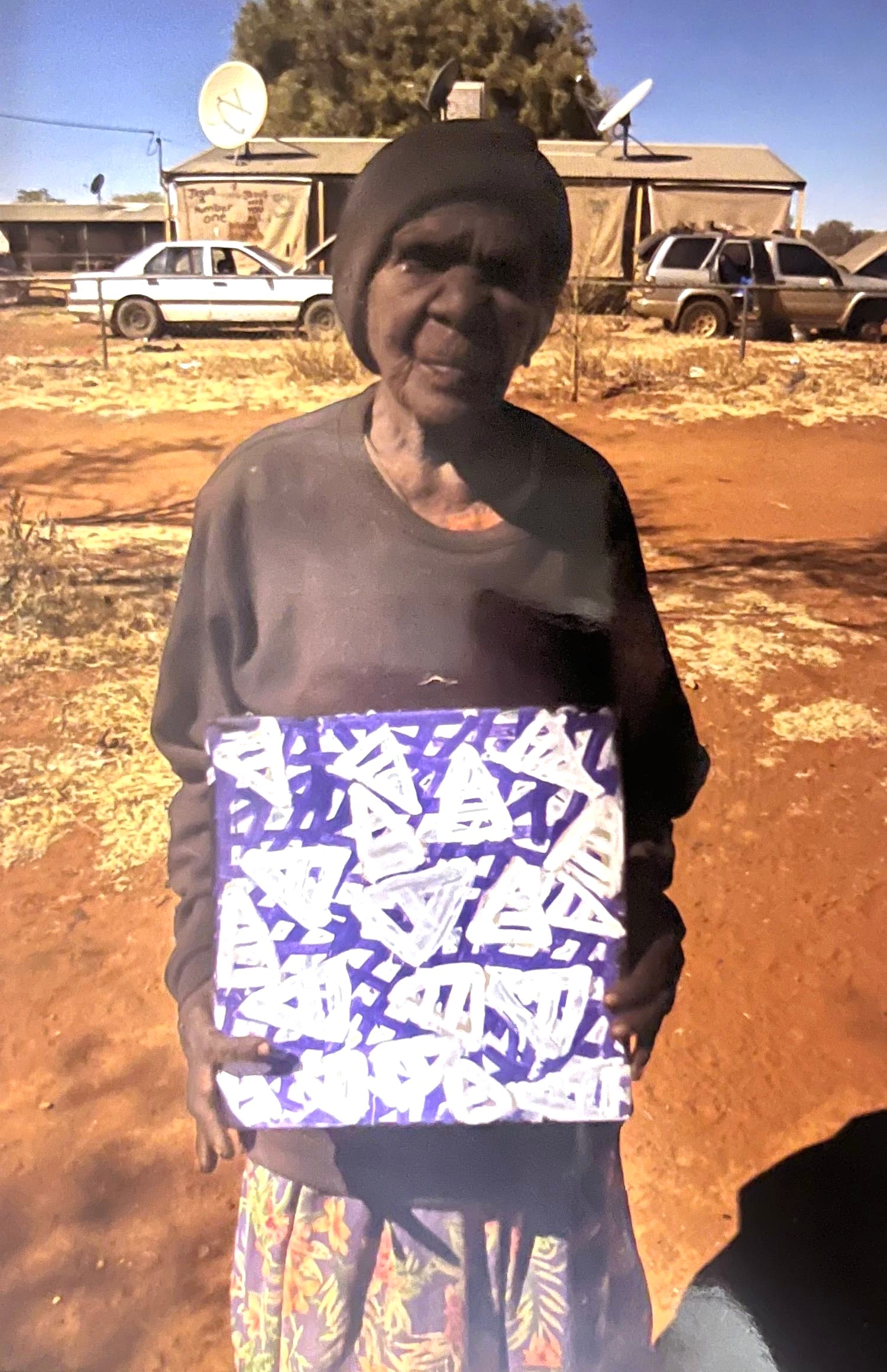 Emily Pwerle holding her small painting representing awelye or women's ceremonies.