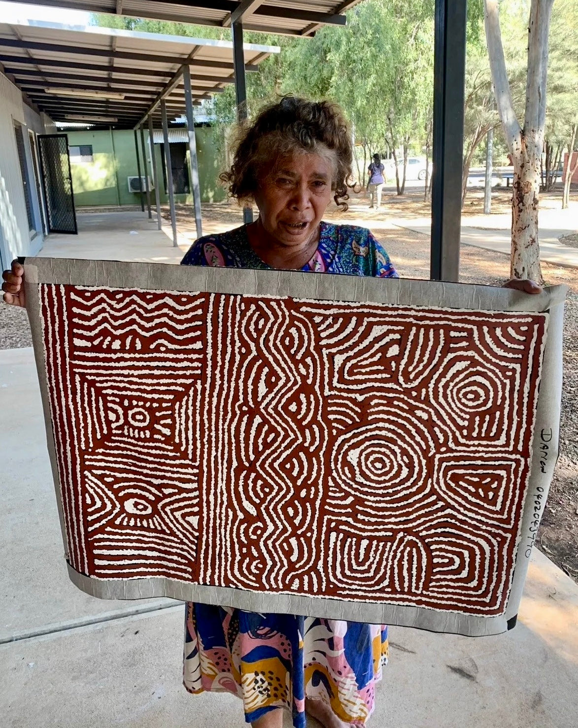 Lorna Brown Napanangka holding her warren creek celebration painting.
