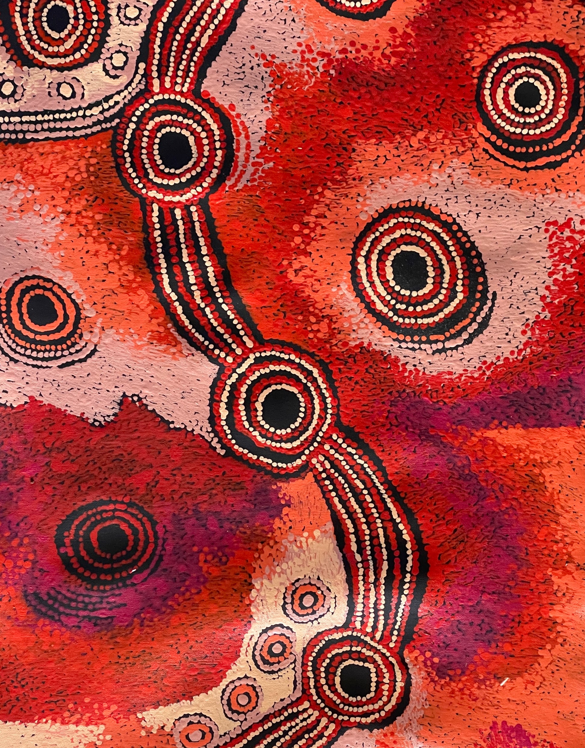 a close-up  of a ainting by Teresa Baker featuring abstract geometric patterns with predominantly red and black colors, representing the creation story of Minyma Malilu Tjukurrpa.