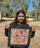 Bernadine Johnson Kemarre holding one of her 30x30cm paintings, representing traditional bush medicine plants.