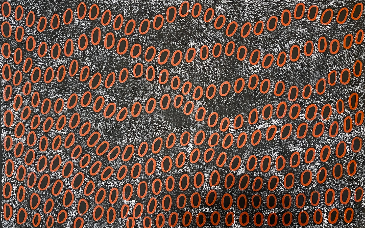 A painting by Ngoia Pollard Napalptjarri showing red oval shapes on a white dotted black background.