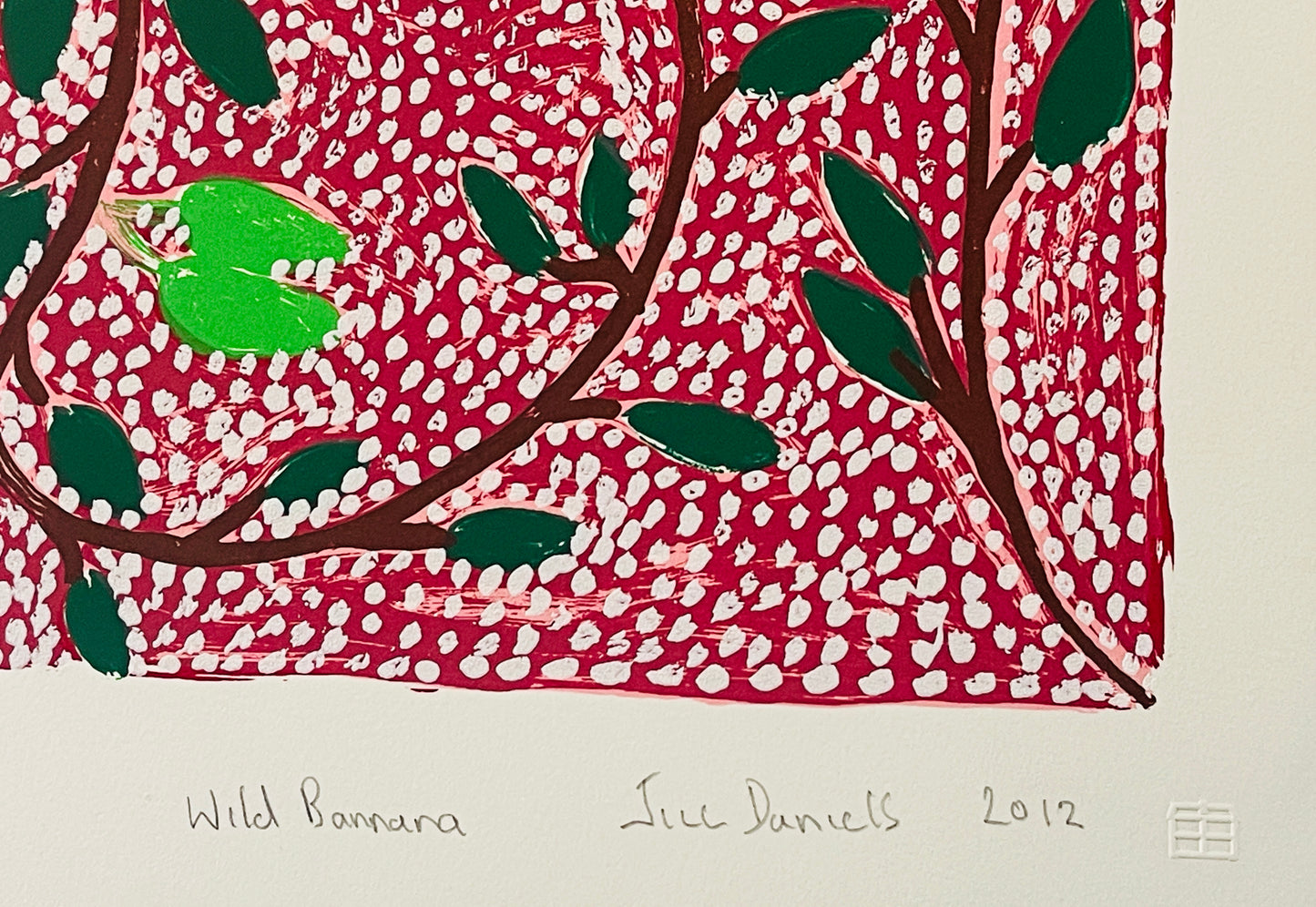 Close-up of a screen print by Jill Daniels 'Wild Banana', artwork depicts leaves and branches on a red and white patterned background