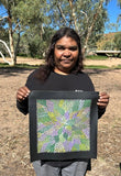 Bernadine Johnson Kemarre holding one of her 30x30cm paintings, representing traditional bush medicine plants.