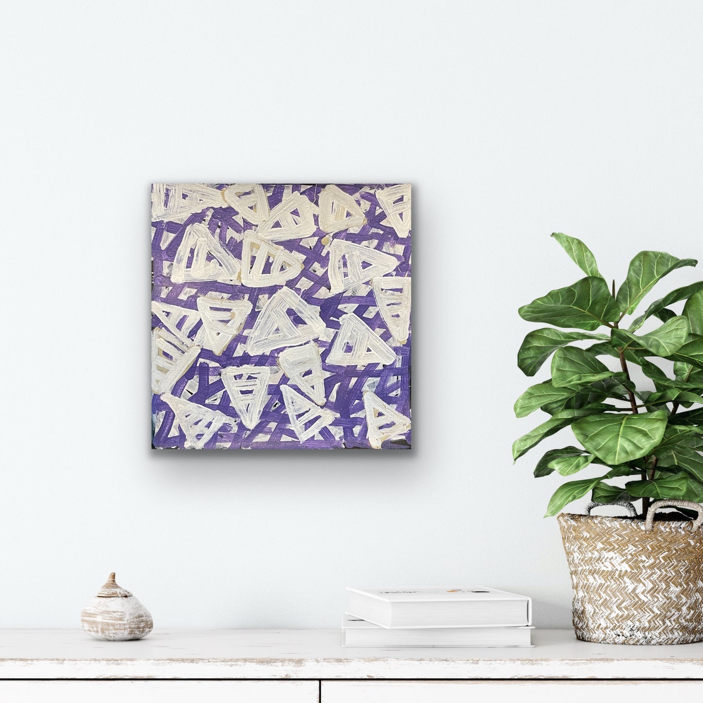 A 30x30 painting by Emily Pwerle with a geometric pattern consisting of white, purple and beige colours, representing awelye or women's ceremonies.