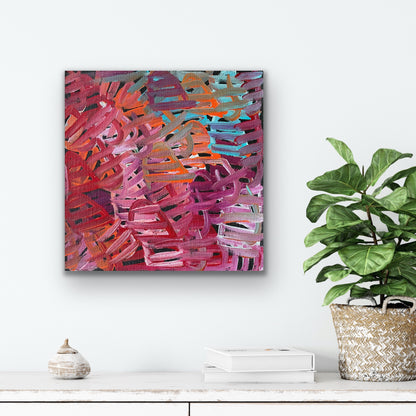 A painting by Emily Pwerle on a white wall above a shelf with decor items and a plant.