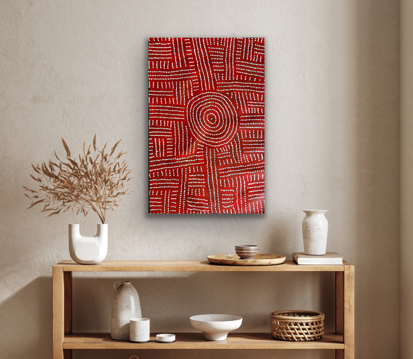 A painting by Bambatu Napangardi hanging on a beige wall above a wooden console table with decorative items.