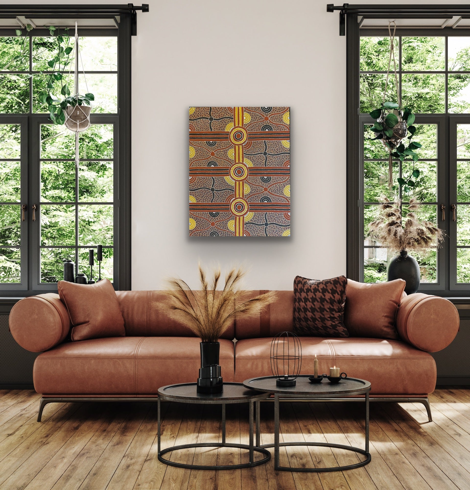 A painting by Kevin Bird Mpetyane depicting mulga seed dreaming hanging in a modern living room with a brown leather sofa and coffee table.