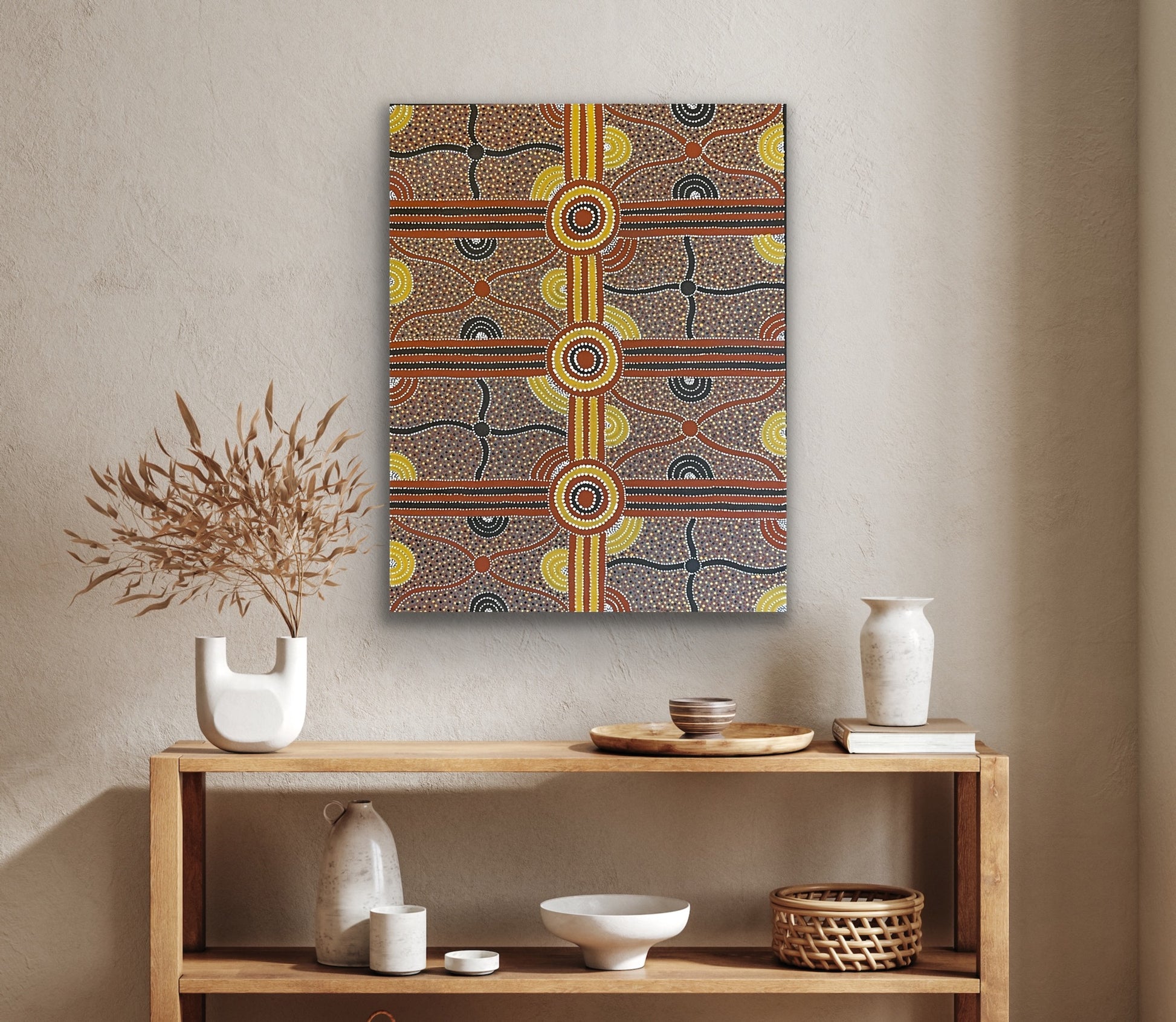 A painting by Kevin Bird Mpetyane depicting mulga seed dreaming hanging on a beige wall above a wooden console table.
