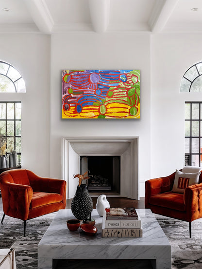 A painting by Lorna Fencer Napurrula depicting yarla or bush potato dreaming hanging in a modern living room with orange chairs, a marble coffee table.