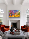 A painting by Lorna Fencer Napurrula depicting yarla or bush potato dreaming hanging in a modern living room with orange chairs, a marble coffee table.