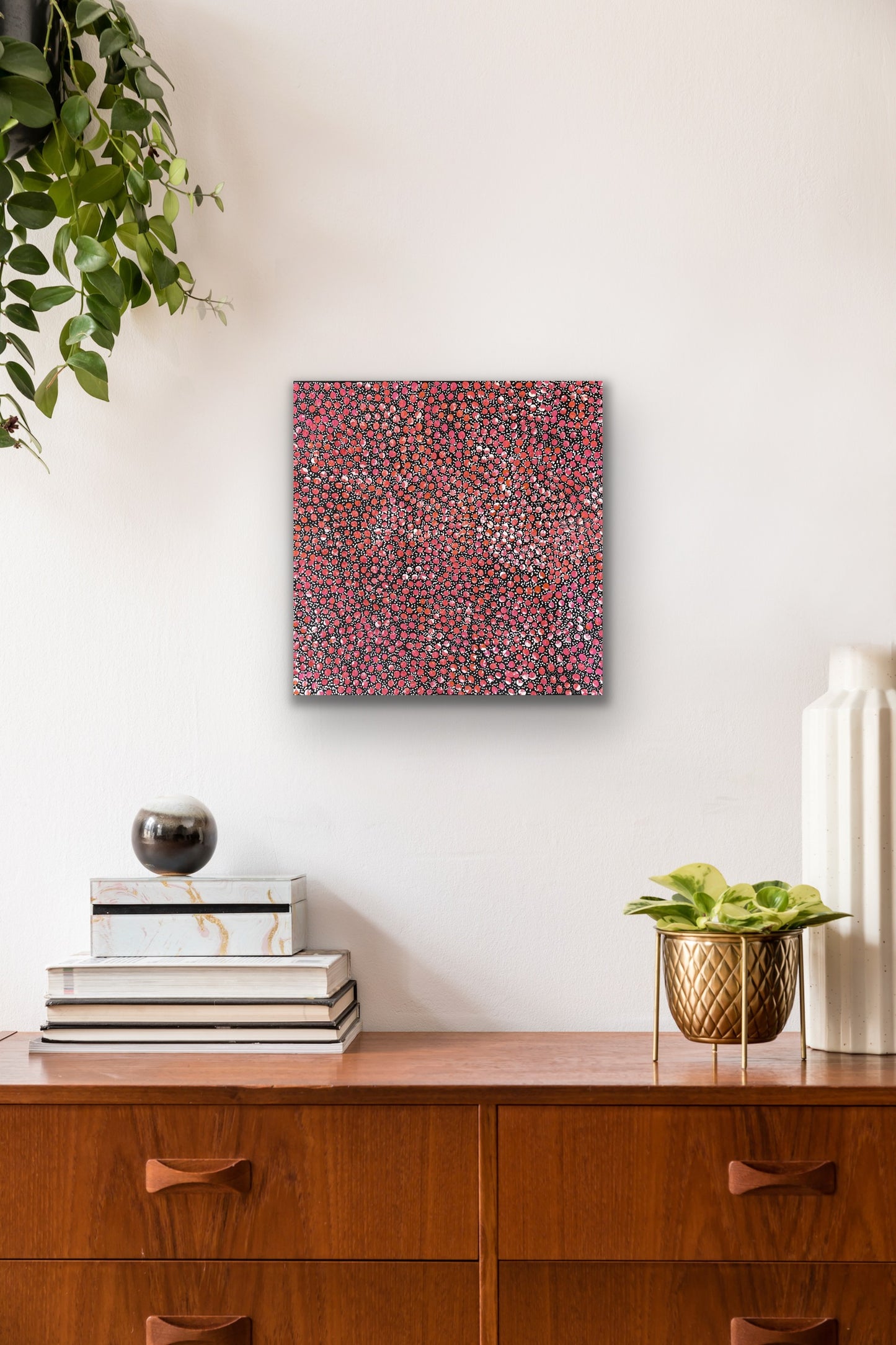 A painting by Eileen Bird Kngwarreye on a wall above a wooden console table with decorative items.