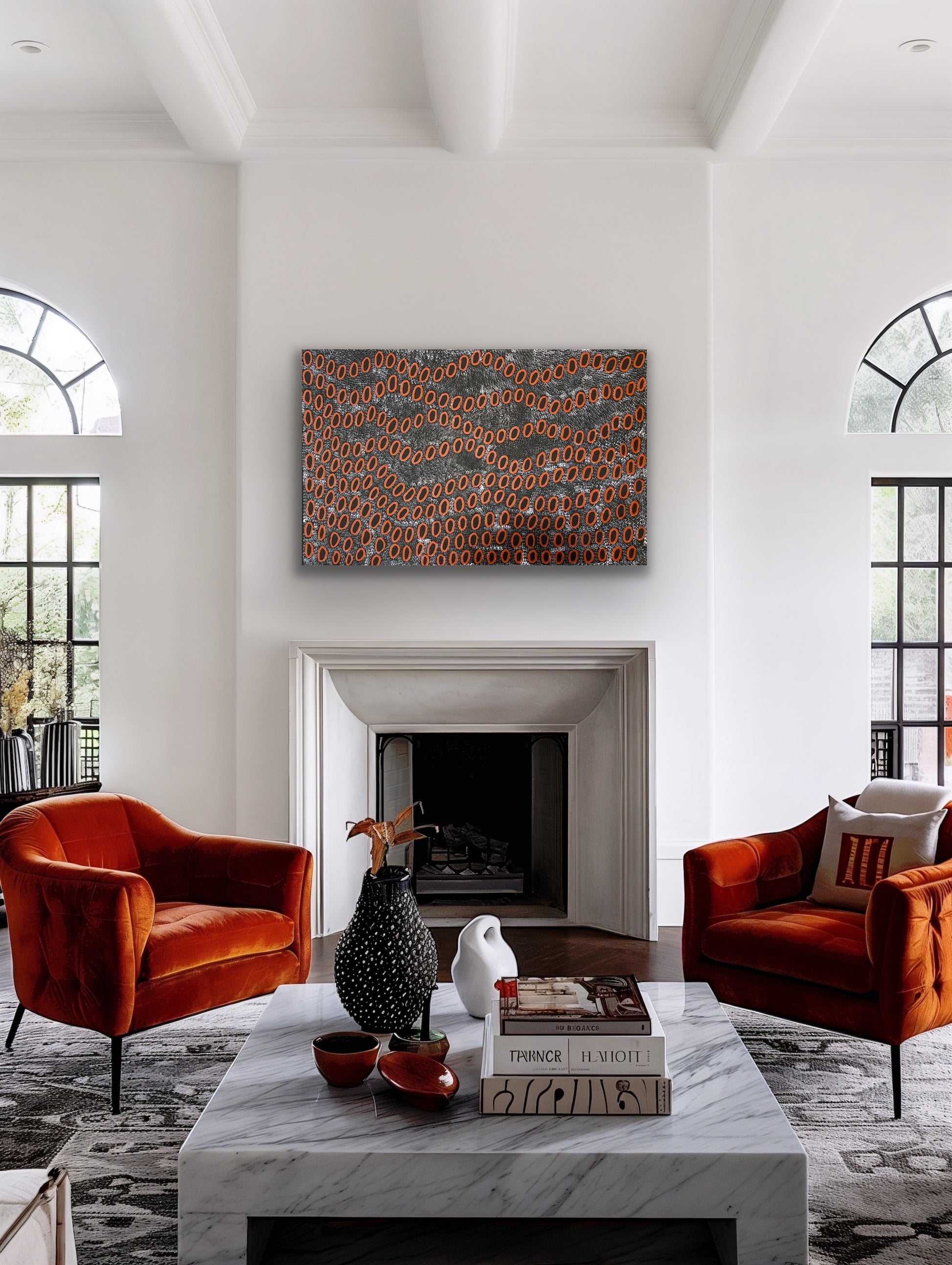 A painting by Ngoia Pollard Napalptjarri hanging in a modern living room with burnt orange chairs, a marble coffee table.