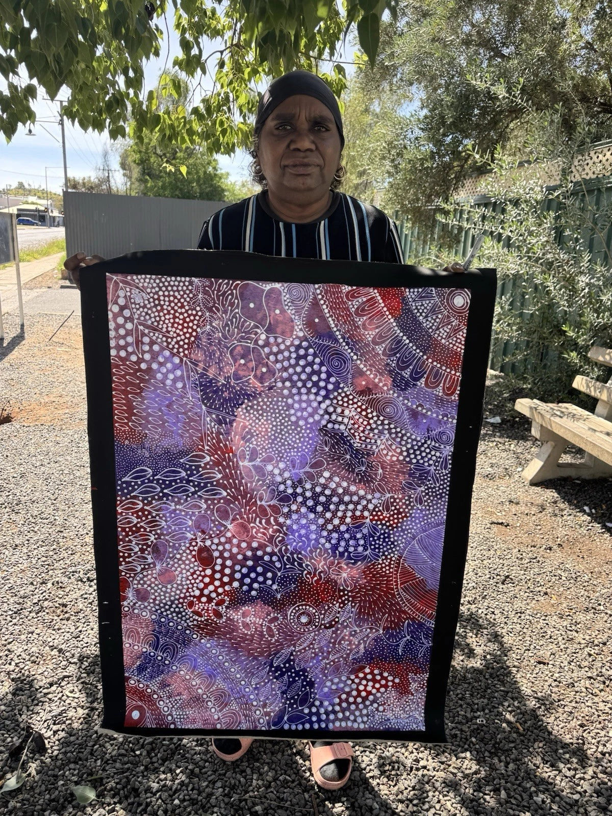 Artist Tanya Bird Mpetyane holding her Ahakeye (Bush Plum) painting.