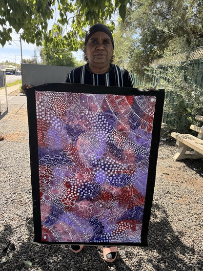 Artist Tanya Bird Mpetyane holding her Ahakeye (Bush Plum) painting.