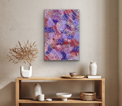 A painting by Tanya Bird Mpetyane hanging on a wall above a wooden console table with decorative items.