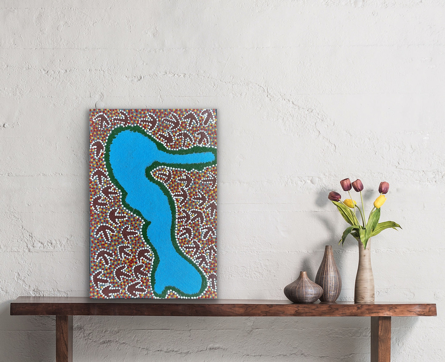 A small painting by Lindsay Bird Mpetyane on a textured wall above a wooden console table.