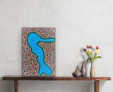 A small painting by Lindsay Bird Mpetyane on a textured wall above a wooden console table.