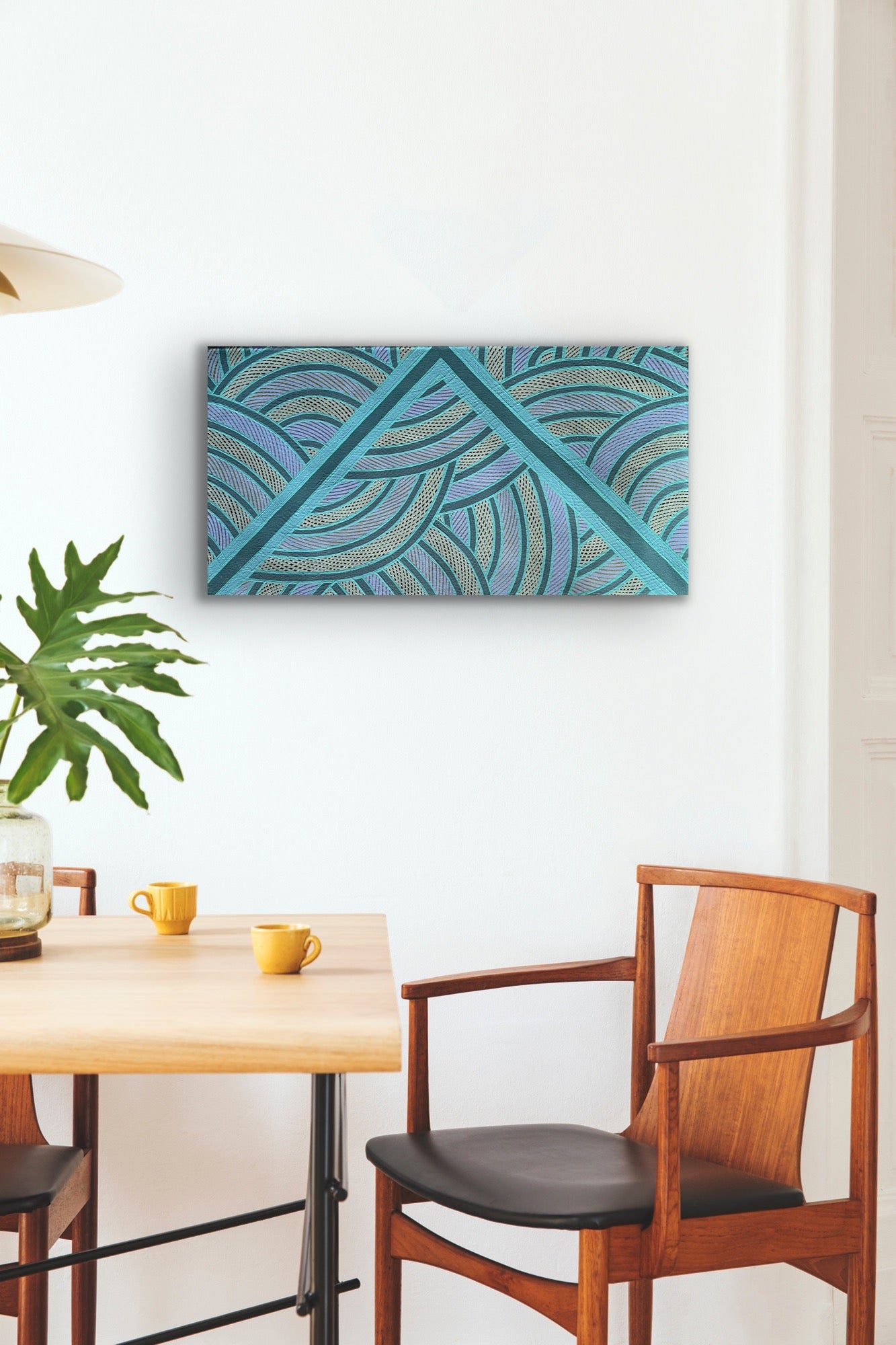 A dining area with wooden table, chairs, and a painting by Ruby Djikarra Alderton.