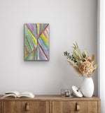 A colourful painting by Mary Morton Kemarre on a wall above a wooden cabinet with decorative items.