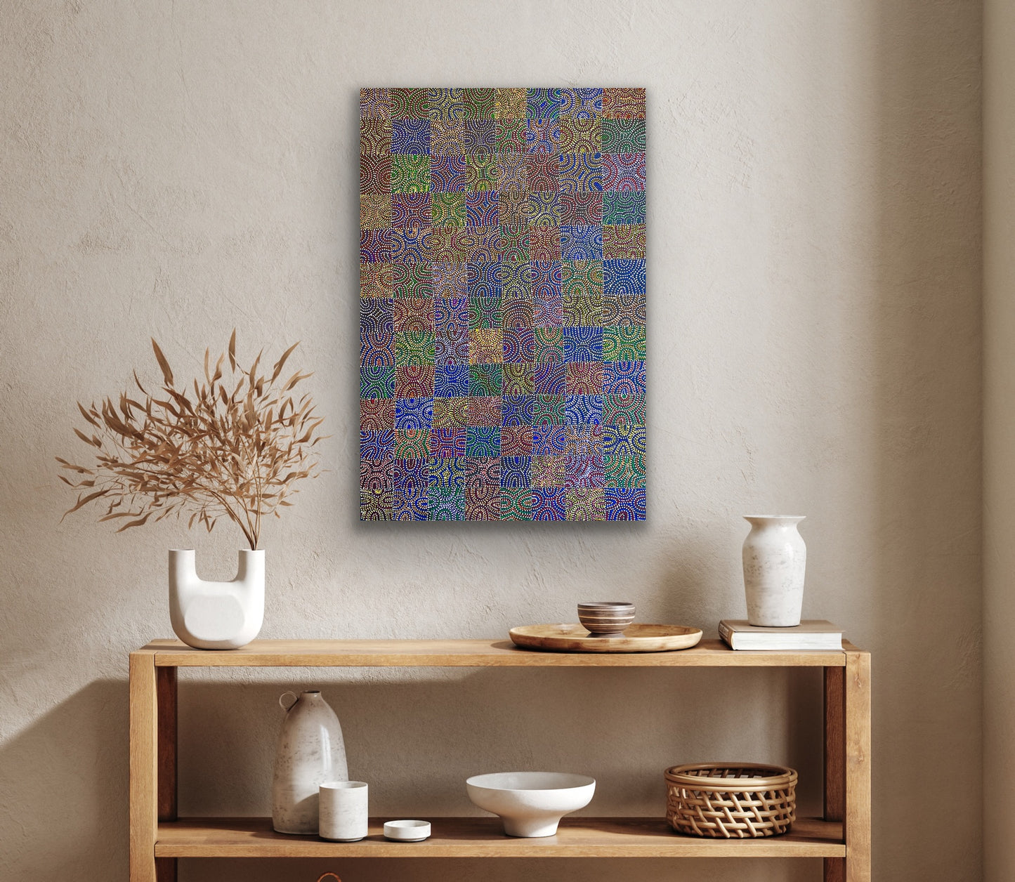 A colourful painting by Lizzie Moss Pwerle hanging on a wall above a wooden console table with decorative items.