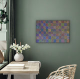 A colourful painting by Lizzie Moss Pwerle hanging on a green wall above a wooden table with a vase and flowers.