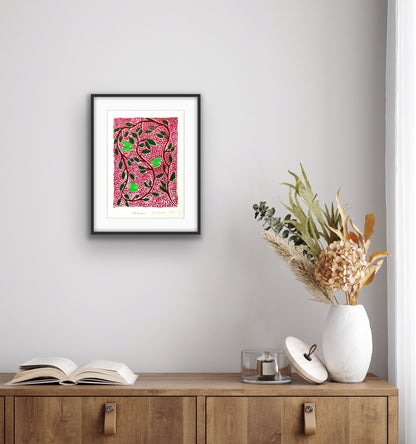 Framed Jill Daniels 'Wild Banana' artwork on a wall above a wooden cabinet with decorative items.