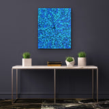 A painting by Selina Numina hanging on a dark wall above a marbel console table with several decorative items.