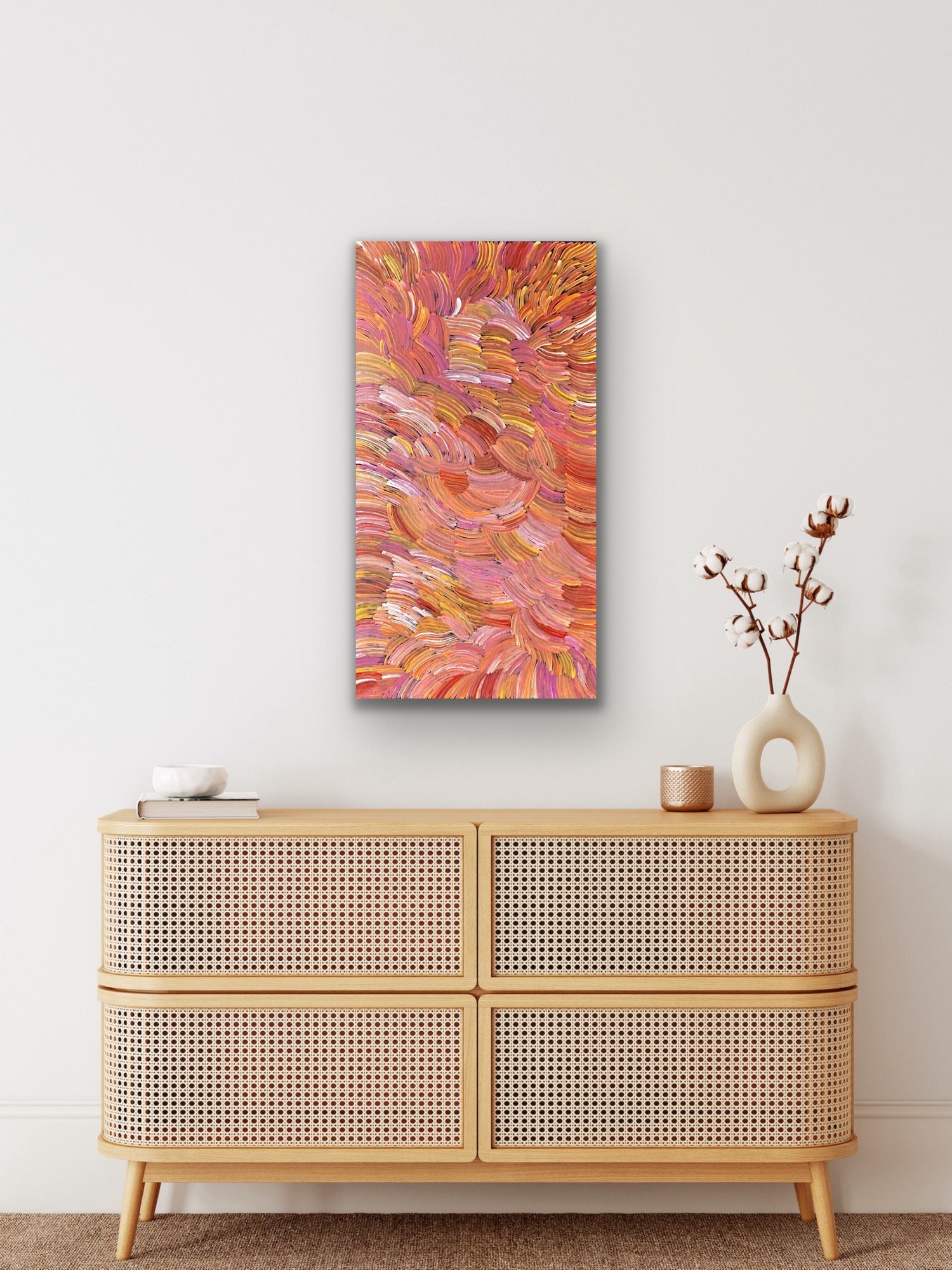 A pencil yam painting by Jedda Purvis Kngwarreye featuring swirling patterns in pink, red, yellow and orange hues.