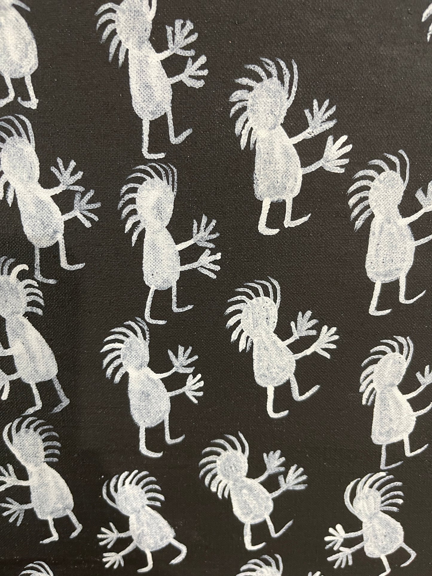 Close-up of a painting on primed linen by Naomi Kantjuriny, featuring a dark background with numerous white figures that represent good and bad spirits.