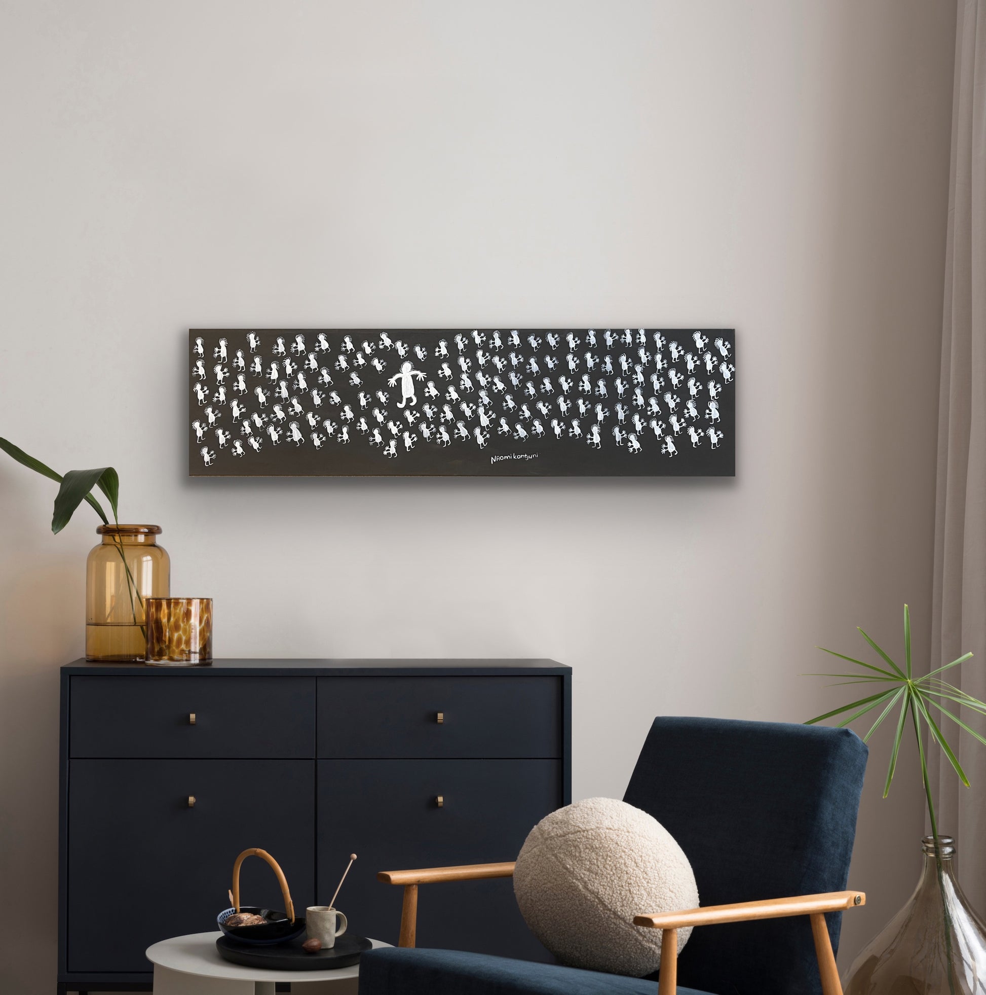 A painting by Naomi Kantjuriny, featuring a dark background with numerous white figures that represent good and bad spirits.