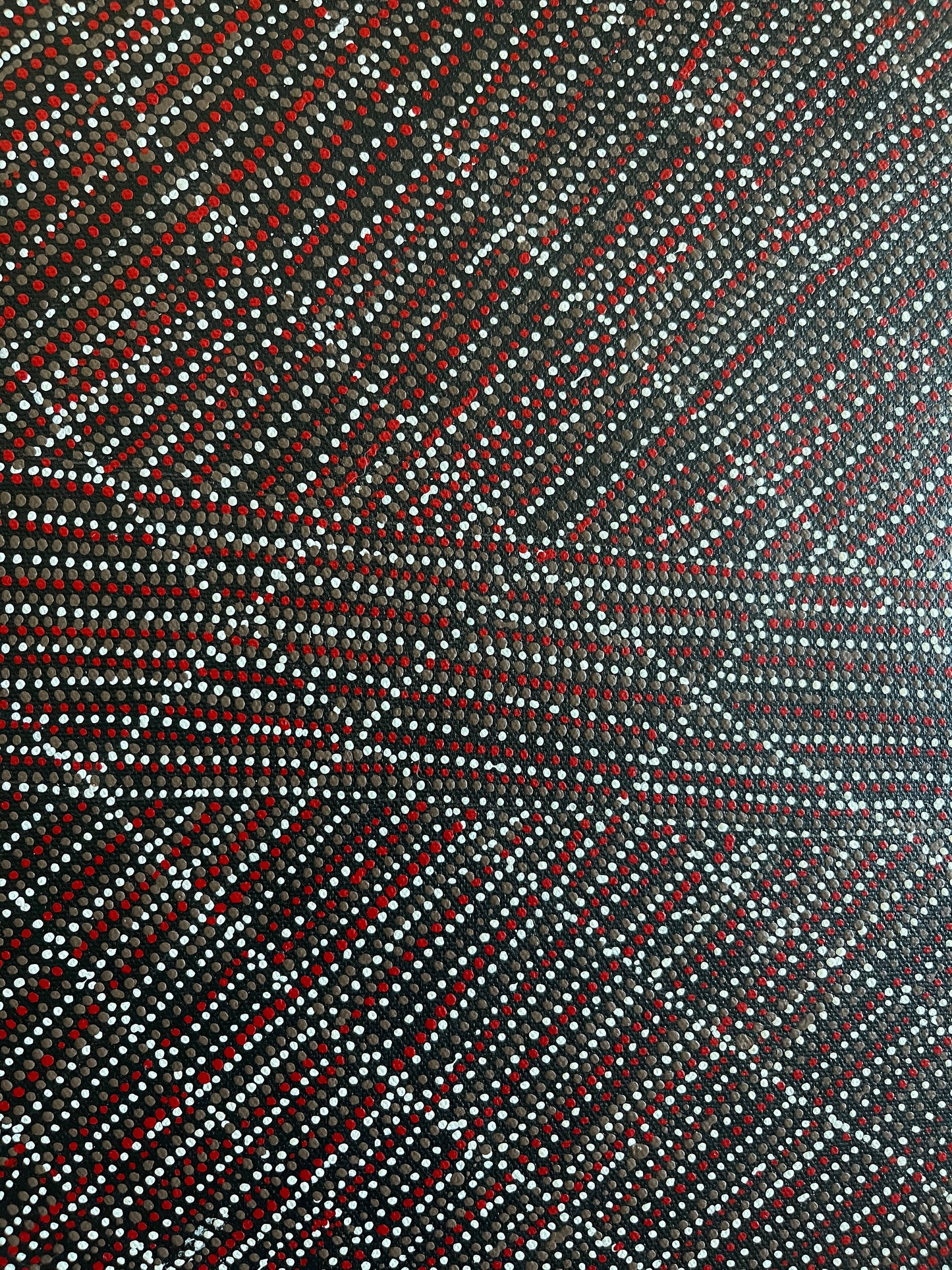 Close-up view of 30x30cm painting by Lizzie Moss Pwerle with a geometric pattern featuring red, grey and white dots on a black background. 