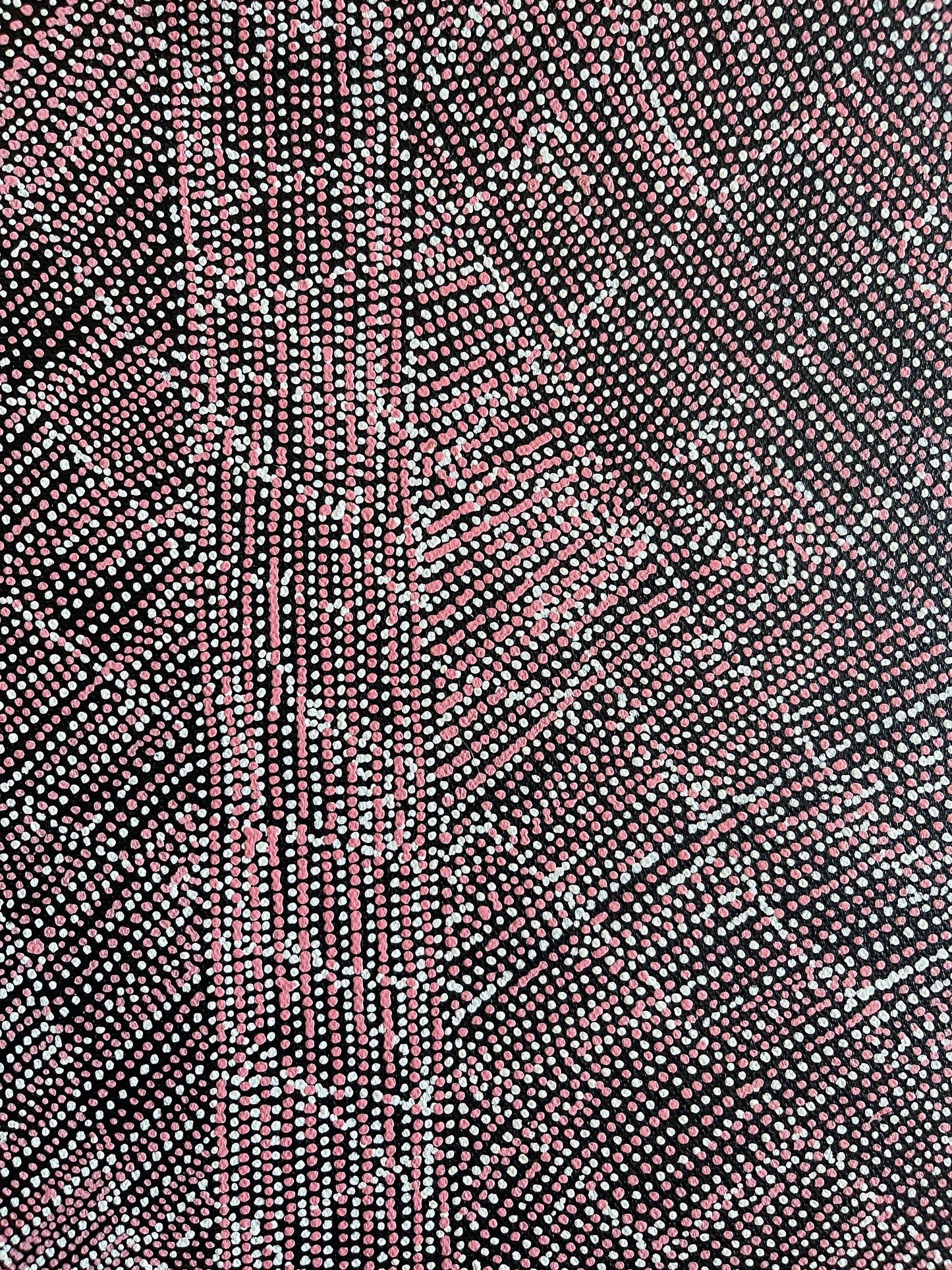 Close-up of a 30x30cm painting by Lizzie Moss Pwerle with a geometric pattern featuring pink and white dots on a black background. 