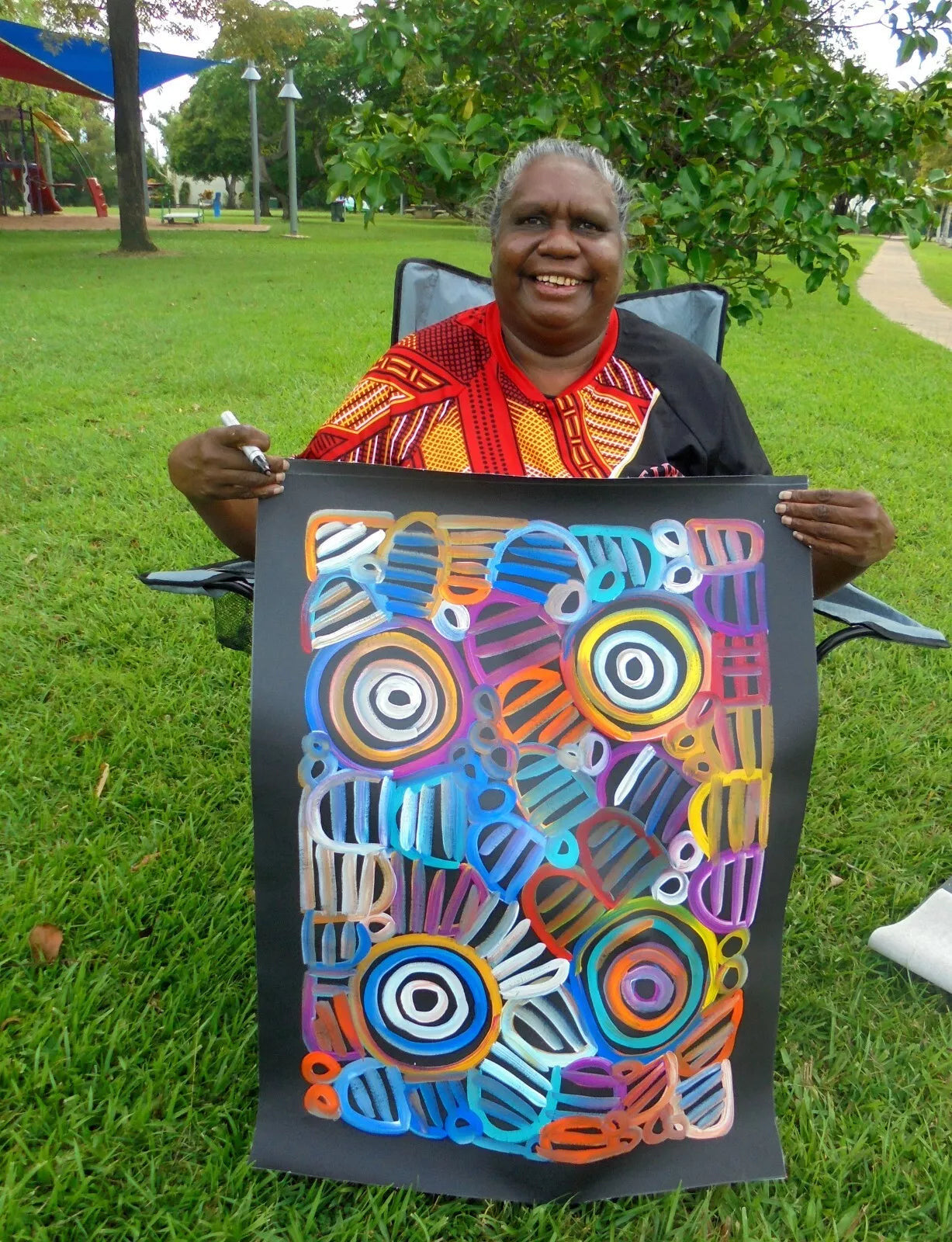 Louise Numina Napananka holding her multicoloured womens body design paintings. 
