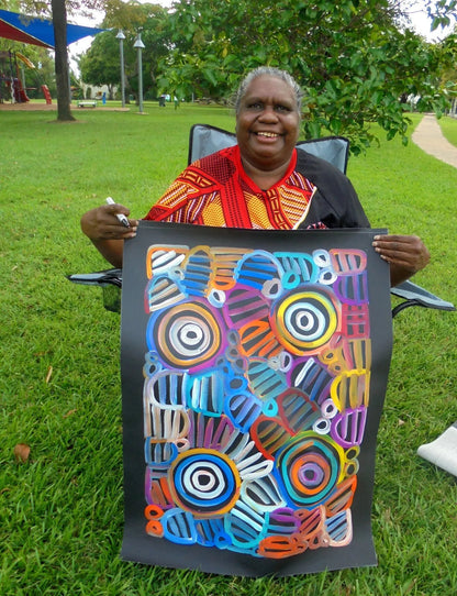 Louise Numina Napananka holding her multicoloured womens body design paintings. 
