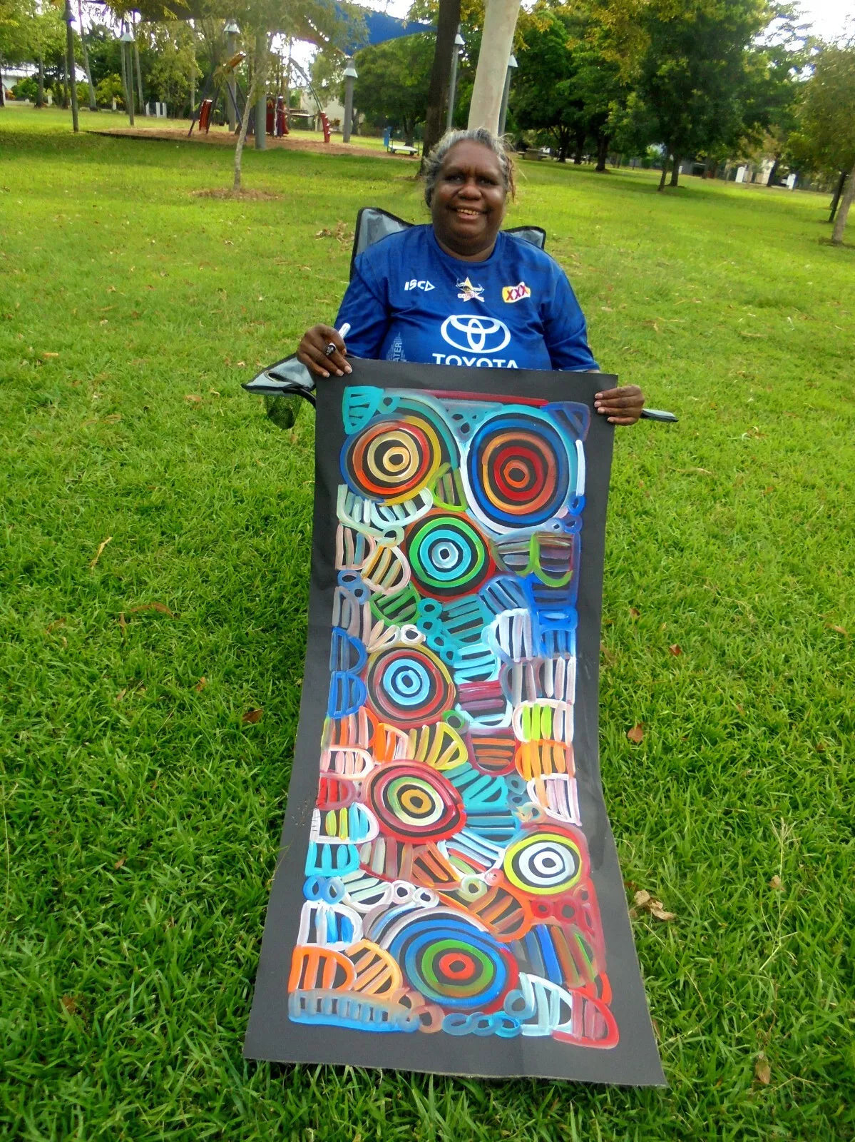 Louise Numina Napananka holding her multicoloured womens body design paintings. 