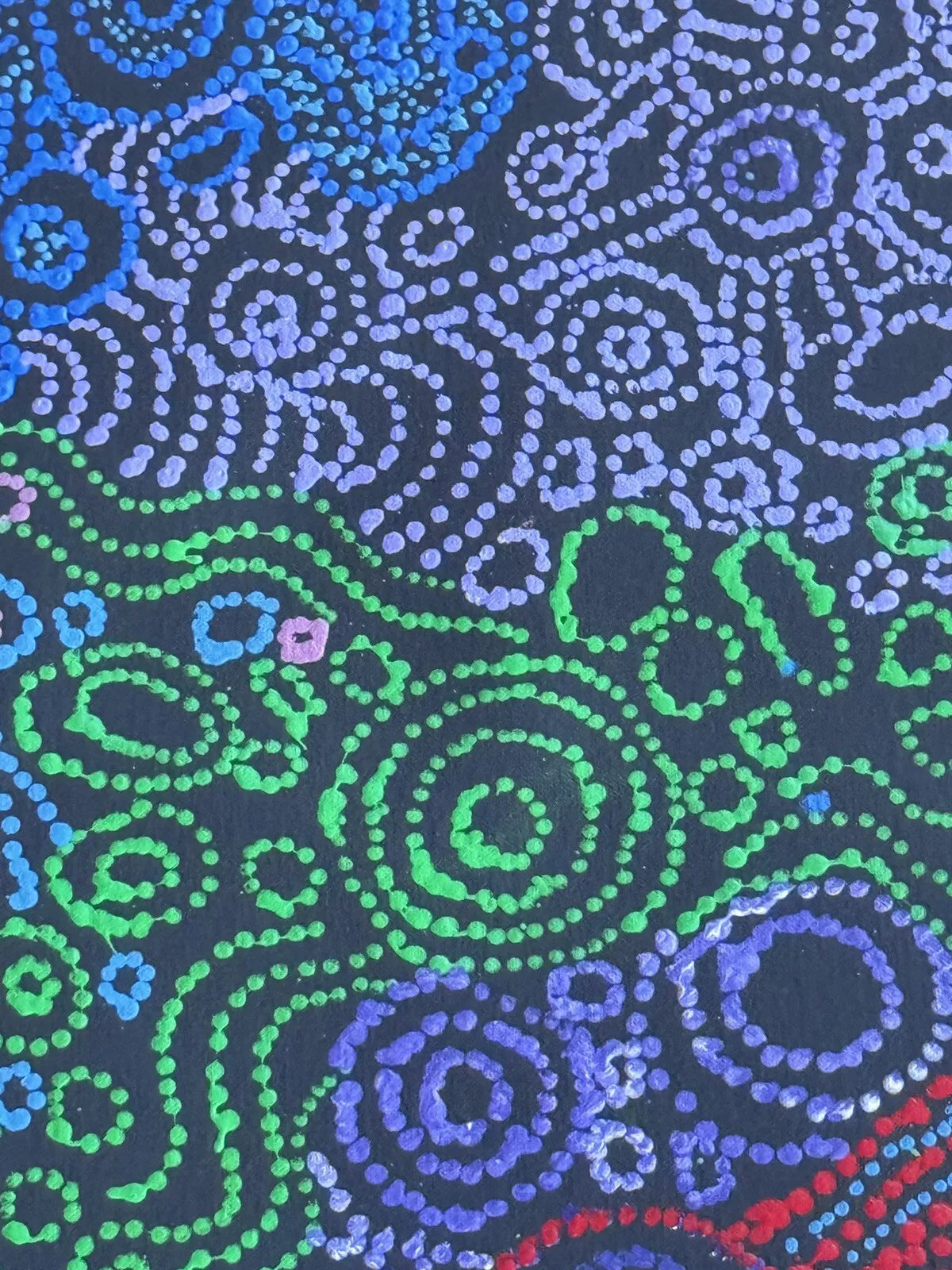 An extreme close-up of a painting by Meredith Curley, featuring intricate dots in blues, greens, purple, pink and red on a primed black canvas.