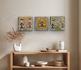 Three Linda Syddick Napaltjarri paintings on a wall above a wooden console table with decorative items.
