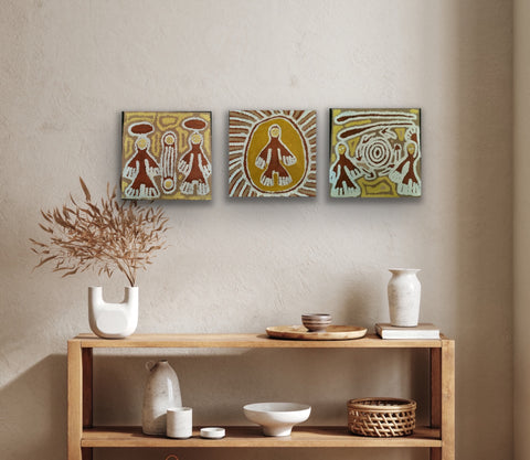 Three Linda Syddick Napaltjarri paintings on a wall above a wooden console table with decorative items.