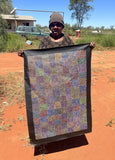 Artist Lizzie Moss Pwerle holding her colourful 90x60cm painting.