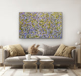 Living room with a gray sofa, decorative pillows, and a coluorful painting by Gloria Petyarre on the wall.