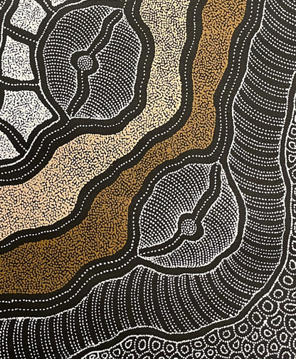 Close-up of a painting by Delvine Pitjara with two organic brown dotted lines surrounded by white dotted shapes on a black background.